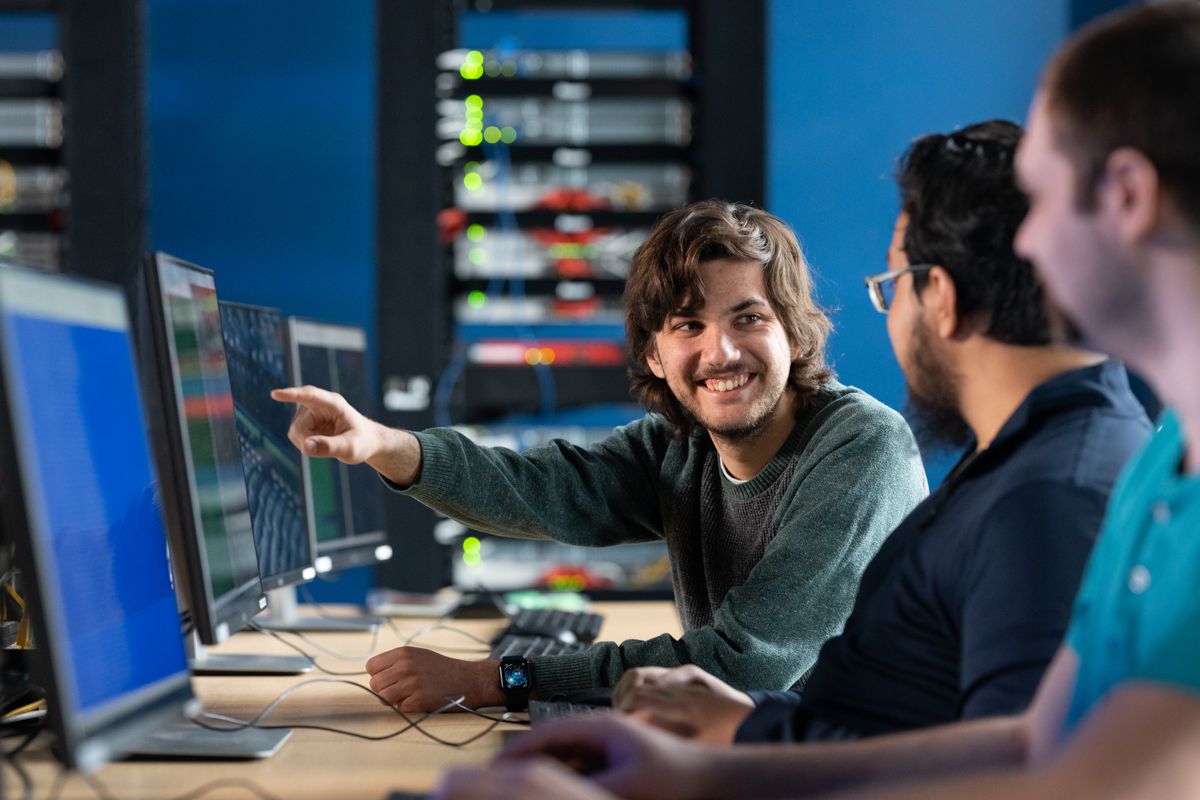 student looking at dual monitor screens with graphs