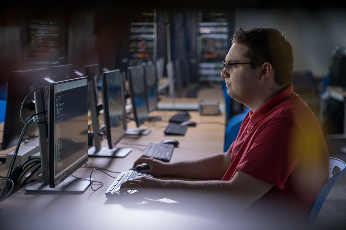 An employee is sitting in front of a computer screen using a keyboard to type.
