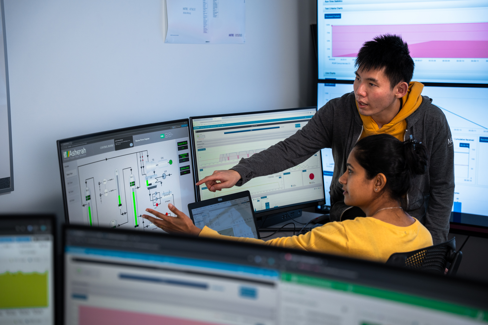 Two students looking at computer screens with computer screens in the background