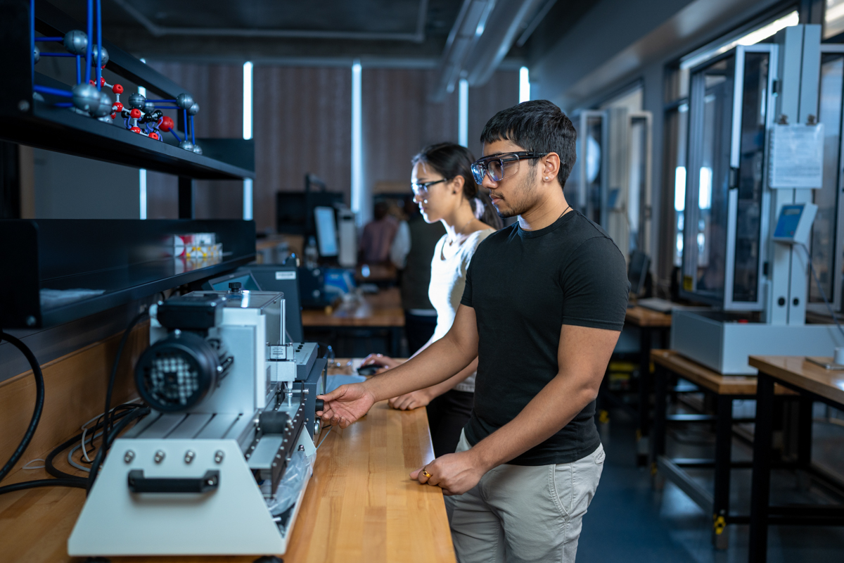 Two students work on engineering equipment.