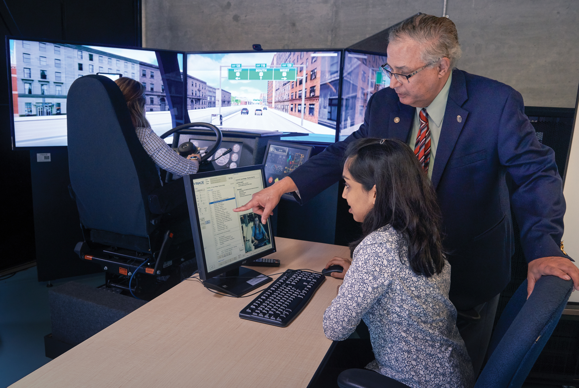 A professor is guiding a student on a computer.
