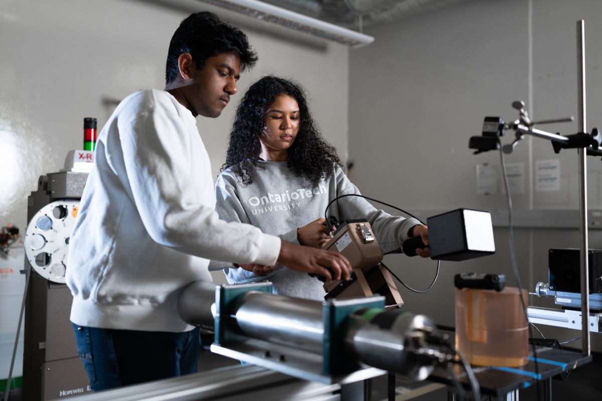 Two students are working on nuclear engineering equipment.