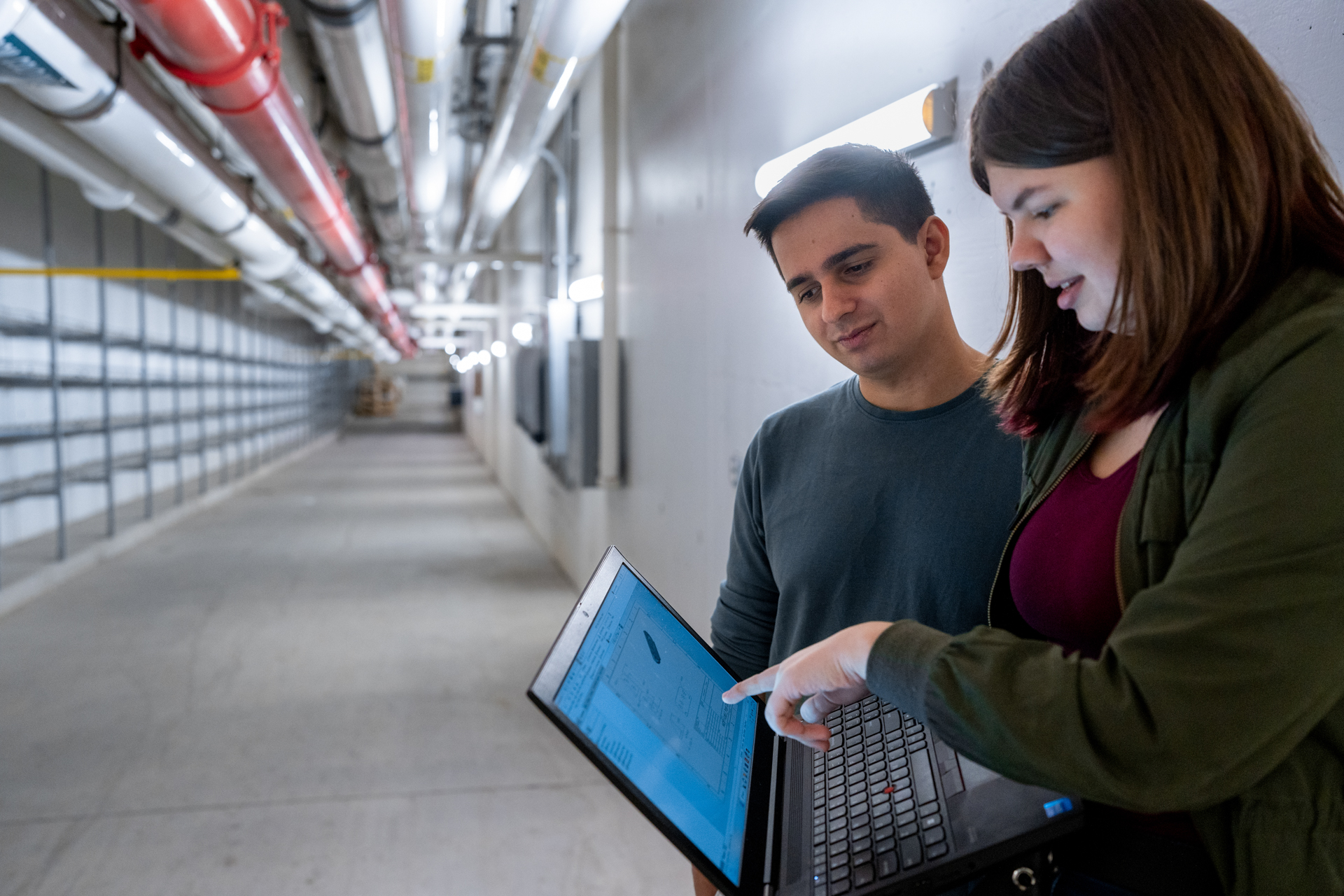 A student shows a fellow student something on their laptop.