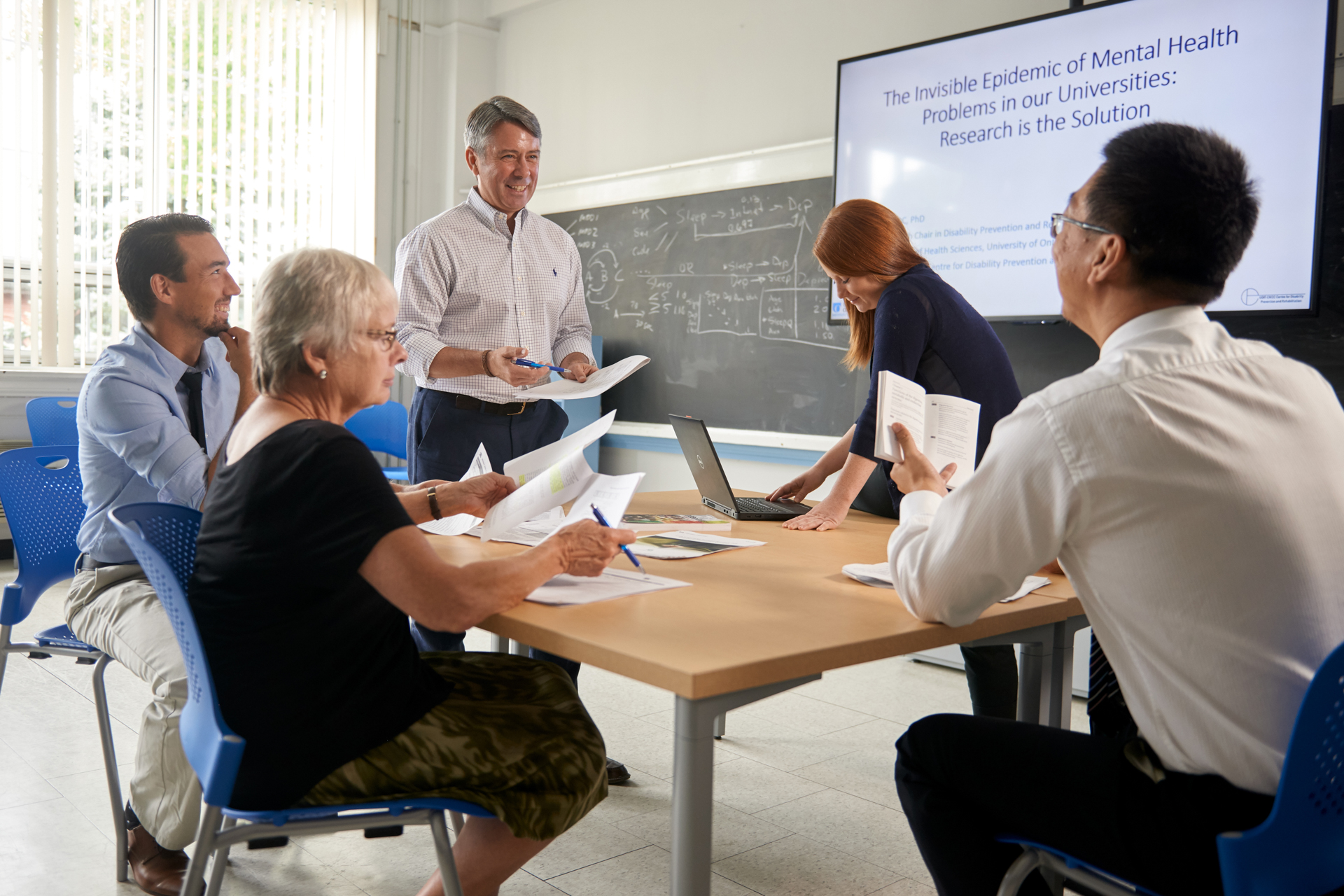 Group of people discussing a presentation around a table.