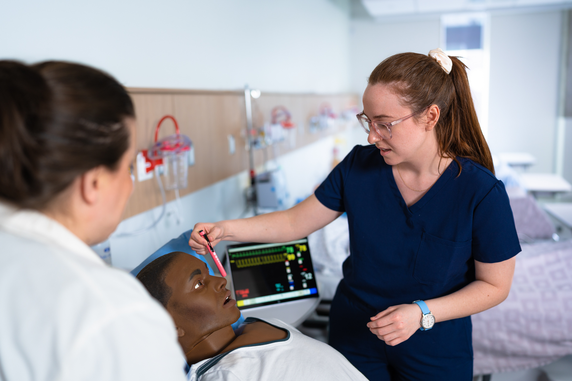 A female student inspects a human-shaped doll for use in nursing.