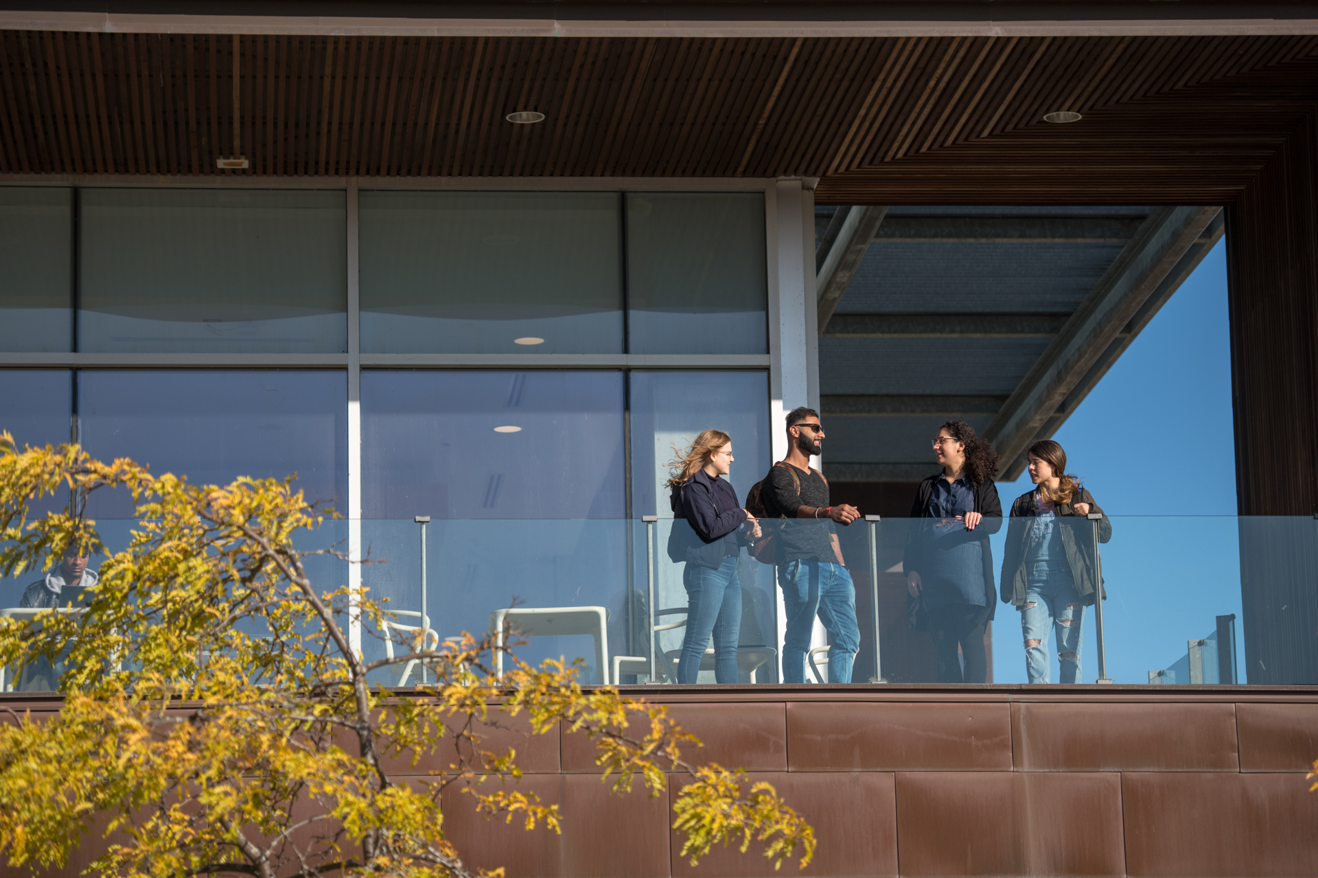 A group of students standing on a balcony outside.