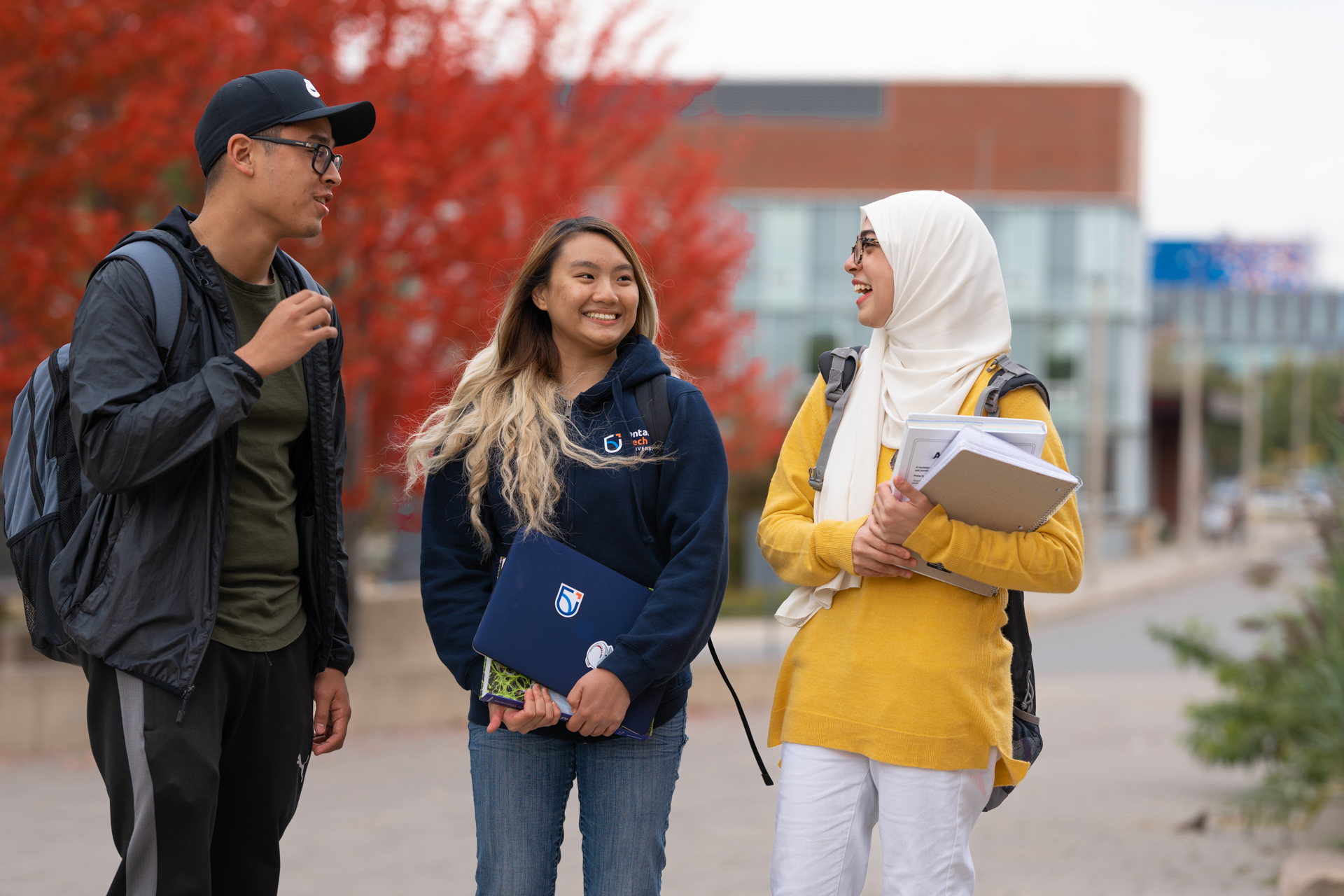 Three students are talking and laughing outside.