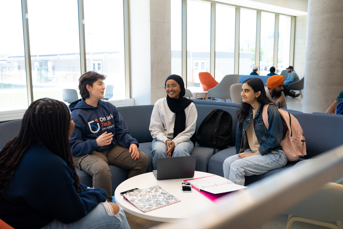 A group of students are sitting on a couch and chatting.