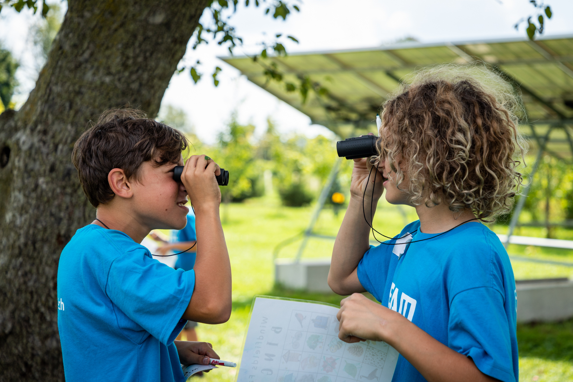 Two children looking at each other through binoculars.
