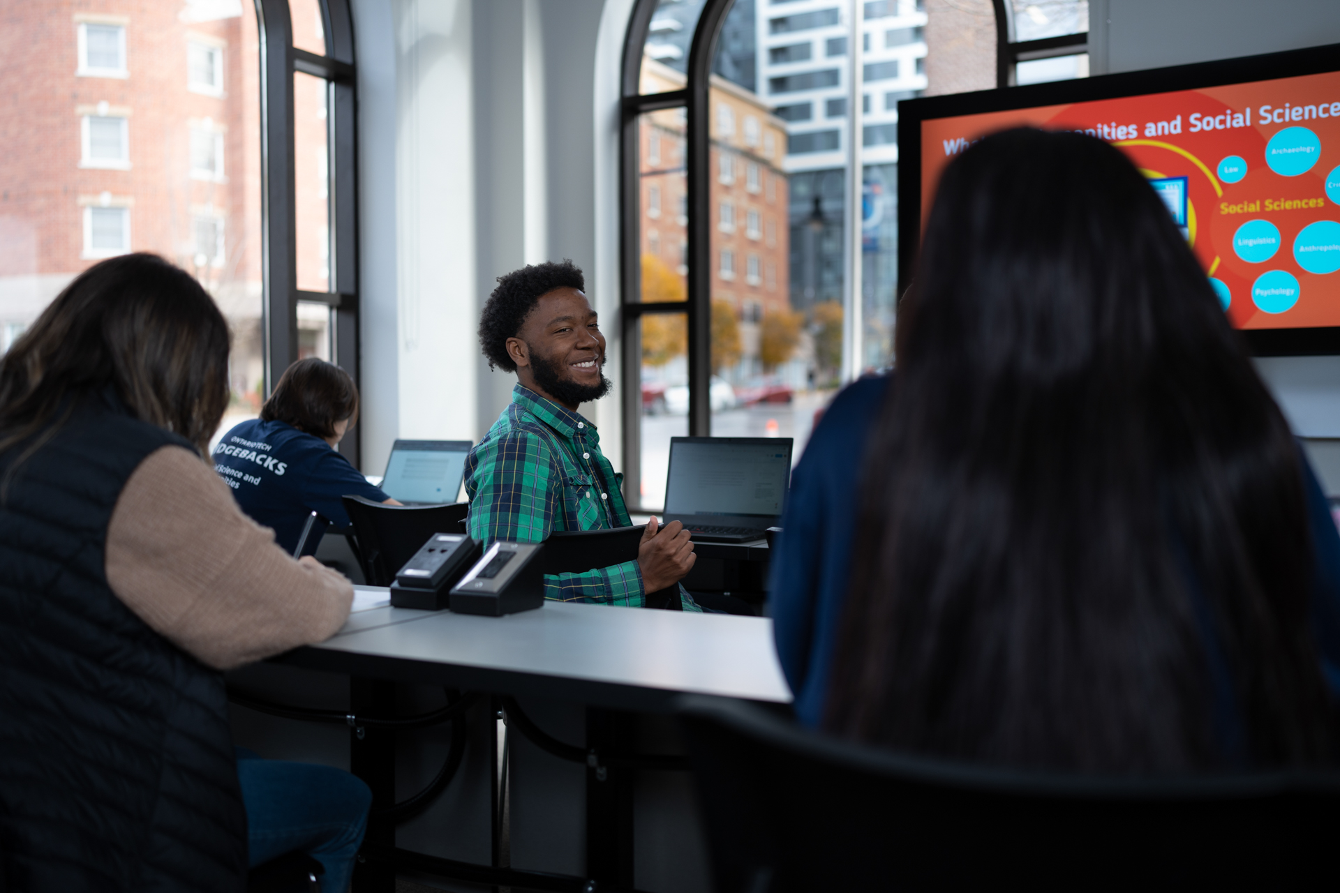 Students sitting in a classroom on the first floor of Bordessa Hall, viewing a presentation.