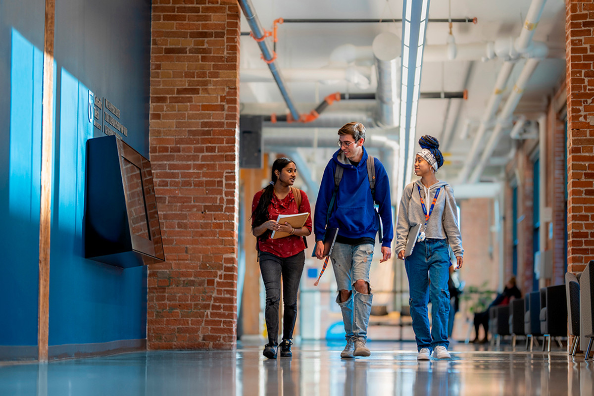 Three students walk down the hallway in Charles Hall