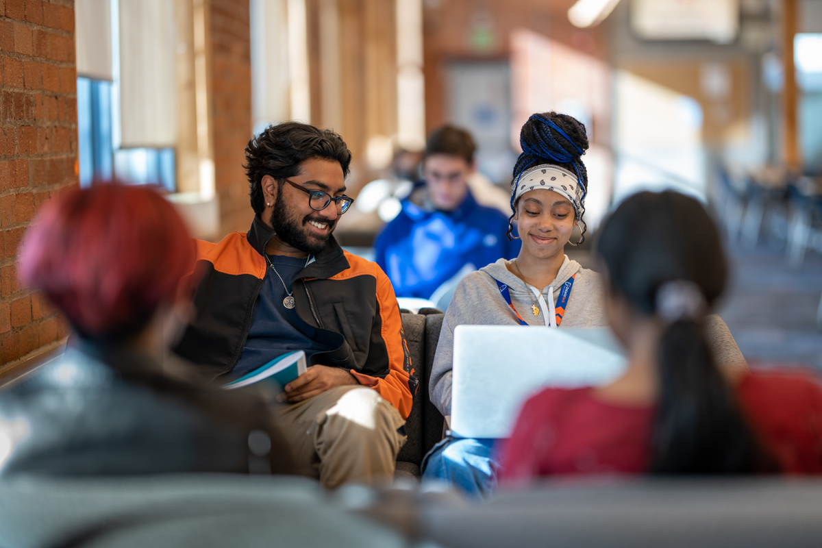 Students sitting and chatting on a couch.