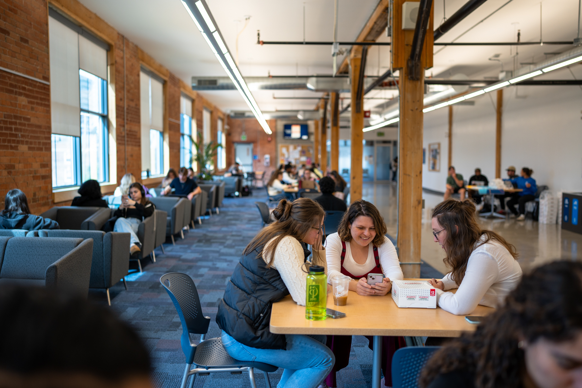 Students inside the downtown campus are studying and smiling at a table.