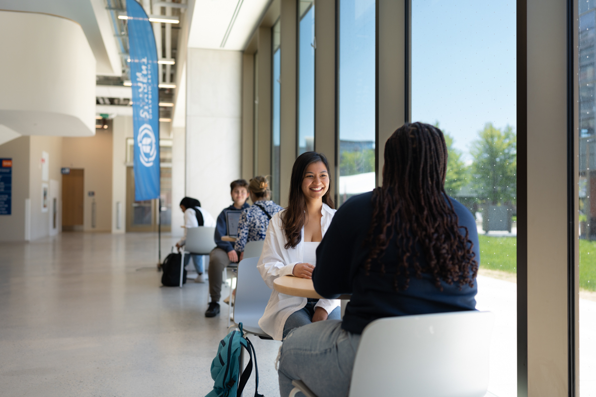 life on campus image showing chairs, common area, glass, north campus, sha, sitting, smiling, students, tables, talking at shawenjigewining hall