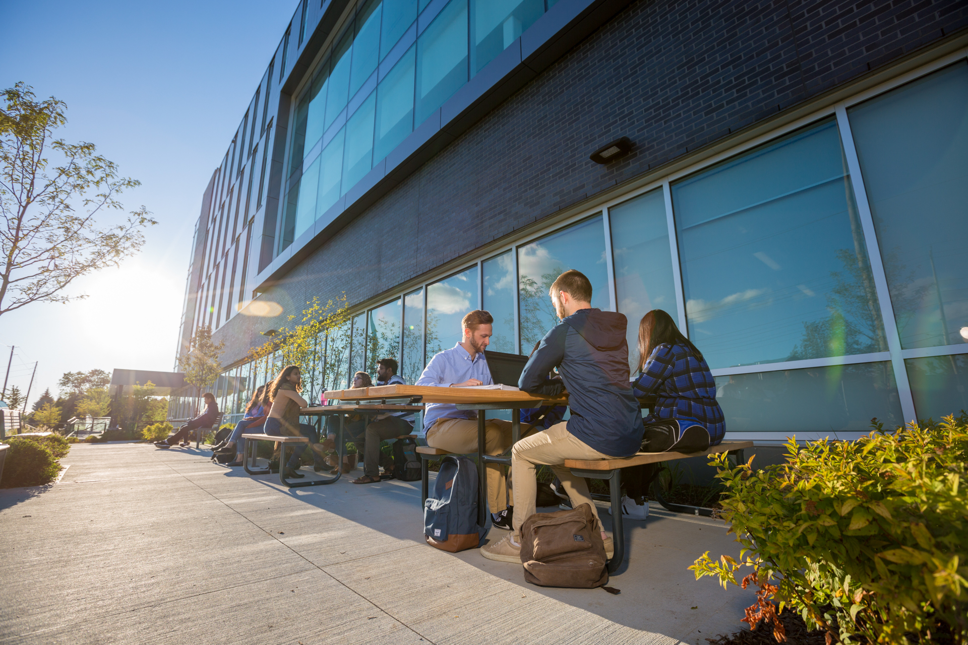 Students are studying outside of the university at a table.