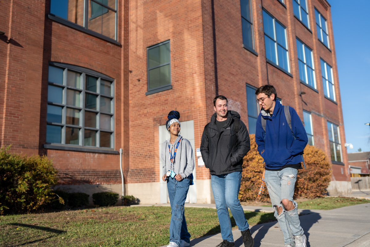 life on campus image showing students, smiling, outdoors, grass, glass, exterior, downtown campus, common area, brick at charles hall