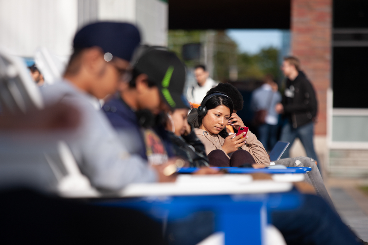 life on campus image showing outdoors, students, studying, sitting, lawn chairs, notebook, phone at software and informatics research centre