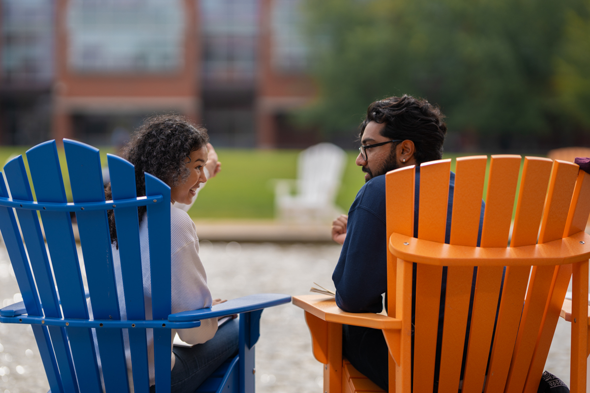 Students sitting outdoors in colourful chairs outside the North Campus Library.